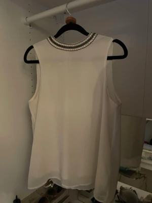 Vit blus med glitter detaljer från Only - Säljer denna fina vita blus från Only med glitter detaljer vid kragen. Storlek 36 och har två knappar i nacken. Inga defekter!