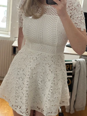 Vit klänning - Kort vit klänning i spets med blommigt mönster och rund hals. Klänningen har korta ärmar och markerad midja som ger en feminin siluett. Perfekt för sommarens alla tillfällen. Jag skulle själv använt den till studenten men hittade en annan. Aldrig använd- alla prislappar kvar. Kostade 699 när jag köpte den. Men priset går att diskutera. <3