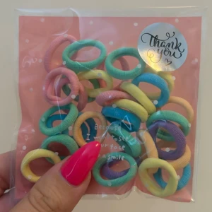 Färgglada hårsnoddar i pastell 30 st - Säljer ett paket med mjuka hårsnoddar i olika pastellfärger som rosa, mintgrön, gul, blå och lila. Perfekta för att göra snygga frisyrer eller bara piffa till looken. Kommer i en söt förpackning med prickar och text.