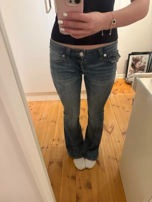 Blå bootcut jeans från True Religion - Säljer ett par blå bootcut jeans från True Religion med klassiska kontrastsömmar och låg midja. Modellen är Joey, low waist flare i storlek 24. Jeansen har fem fickor och en snygg tvättad look. Perfekta för dig som gillar en avslappnad men trendig stil. Nypris 1299. Skriv om du har frågor eller vill ha fler bilder 💕