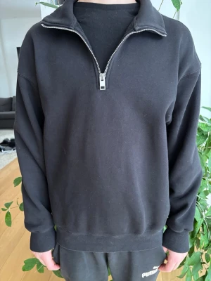 Svart half-zip hoodie - Säljer en svart sweater med half-zip dragkedja och hög krage. Tröjan har ribbade muddar vid ärmslut och nederkant, samt en clean och enkel design utan tryck eller logga. Perfekt för en chill och stilren look. Materialet känns mjukt och bekvämt. Funkar för eb mindre M men sitter bäst på S.