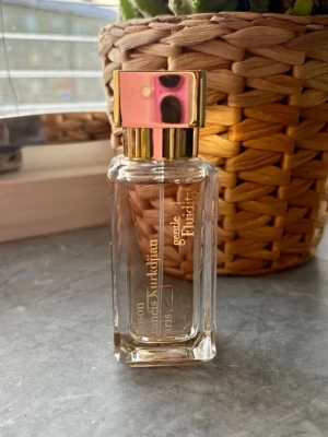 Maison Francis Kurkdjian Gentle Fluidity gold  - Elegant parfymflaska från Maison Francis Kurkdjian med namnet Gentle Fluidity gold. Flaskan är genomskinlig med guldiga detaljer och har en fyrkantig form samt en lyxig guldfärgad kork. Perfekt för dig som gillar exklusiva dofter. 35ml. Ny