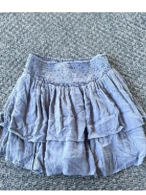 Ljusblå volangkjol med resår - Söt ljusblå kortkjol med volanger och bred resår i midjan. Kjolen är tillverkad i ett lätt bomullsmaterial som ger en luftig känsla. Perfekt för dig som gillar en feminin och avslappnad stil.