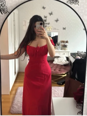 Röd långklänning med snörning - Säljer en röd långklänning med offshoulder och snörning framtill. Klänningen har en figurnära passform och är tillverkad i ett mjukt bomullsmaterial. Perfekt för dig som vill ha en elegant och feminin look.