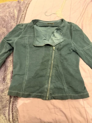 Grön skinnjacka med asymmetrisk dragkedja - Snygg grön skinnjacka med cool asymmetrisk dragkedja framtill och markerade sömmar. Jackan har en modern, figurnära passform och en stilren krage. Perfekt för dig som vill ha en trendig look med edge.