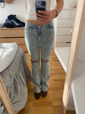 Ljusblå bootcut jeans med hål - Säljer ett par ljusblå bootcut jeans ifrån nelly med hål, i storlek 34. de är lite slitna längst ner, men inget som är sönder💕