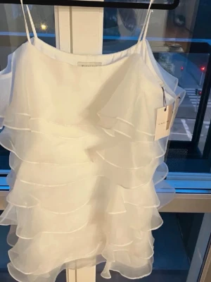 Vit volangklänning från By Malina - Supersöt vit klänning från By Malina i modellen ”Kami” med tunna axelband och flera lager volanger som ger en luftig och romantisk känsla. Perfekt för sommarens alla tillfällen exempelvis student och midsommar. Klänningen är kort och har en lätt, flowy passform. I strl M och helt oanvänd endast testad för bilderna. Inga defekter!! Säljs inte längre, nypris:2599 kr mitt pris:999 kr