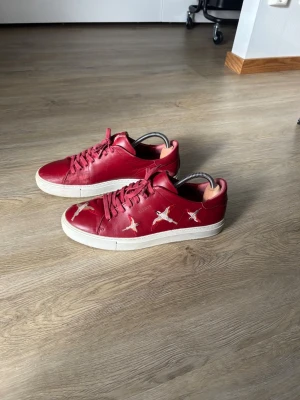 Axel Arigato Bird Sneaker - Snygga röda sneakers i läder med vita broderade fåglar på sidorna. Skorna har vita sulor och matchande röda skosnören. Perfekta för dig som vill sticka ut med en unik och trendig stil. Över lag i mycket bra skick