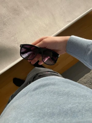 Solglasögon  - Snygga svarta solglasögon med bred plastbåge och mörka tonade glas. Klassisk och stilren design som passar till de flesta outfits. Perfekta för soliga dagar och ger en cool vibe.