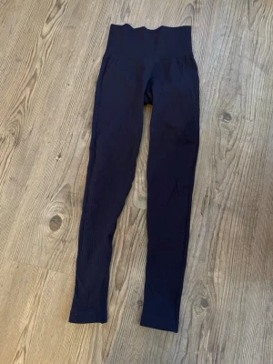  110kr för två par träningstights, Mörkblåa samt gråa  - Gråa och mörkblå träningstights med hög midja och sömlös design säljes. Stretchigt material som sitter tajt och bekvämt. Tightsen är i bra skick men använda i skumgummi grop (foampit) vilket gör att de fastnat ”ludd” på dem som jag inte lyckats få bort. Säljer dem för 80kr styck eller båda för 110kr. OBS! Köparen står för frakt. Pris kan diskuteras. 