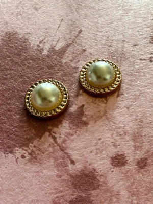 Guldiga örhängen med pärldetalj - oanvända  - Snygga runda örhängen med en stor vit pärla i mitten och en dekorativ guldfärgad kant. Perfekta för att ge din look en elegant touch. Klassisk design som passar till många stilar. - Då jag själv gör dom får man nya och oanvända 