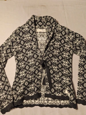 Nyskick ! Mönstrad kofta från Odd Molly - Säljer en svart och vit kofta från Odd Molly med snyggt stickat mönster och knytband framtill. Koftan har långa ärmar, mjukt material och fina detaljer längs kanterna. Perfekt för lager på lager under kyliga dagar.