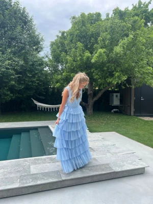 Ljusblå balklänning med v-ringning och volang - Säljer min älskade fina balklänning nu när det är dags för bal. Endast använd förra året på min bal och jag älskade den! Så fin med mycket volanger och en fin v ringning. Finns ej kvar på hemsidan! Världens finaste balklänning!