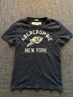 Vintage 2000’s Abercrombie t-shirt - Säljer en eftertraktad marinblå T-shirt från A&F. Vintage 2000’s-modell | storlek S | fint skick 9/10 | svår att hitta idag, särskilt i denna modell och färg. Kan även gå ner lite i pris vid snabb affär. Sliten design 😊