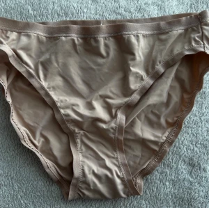 Två par trosor i beige och vinrött - Ny pris 179kr. Säljer två par klassiska trosor i mjukt och stretchigt material. Ena paret är beige och det andra vinrött, båda med enkel design och smala sömmar. Perfekta för dig som gillar bekväma och stilrena underkläder.