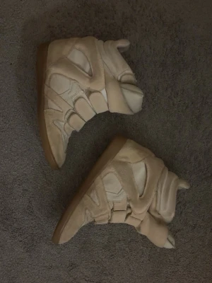 Beige höga sneakers med kardborre - Isabel marant skor äkta, se sula! Se även bild för defekt! Innanför sulan har det gått sönder lite. Men inget som syns med skon på! (Råkade fastna i något) har ej tvättat dom. Storlek 39. 