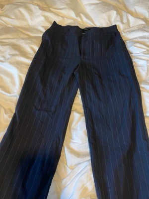 Mörkblå randiga kostymbyxor från pull&bear  - Mörkblå kostymbyxor från pull&bear med tunna vita kritstrecksränder. Byxorna har raka ben och klassisk passform. Storlek XL