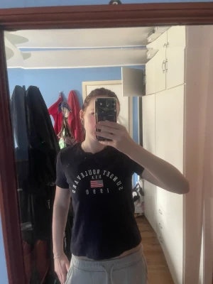 Mörkblå Sunset Boulevard t-shirt H&M - Mörkblå t-shirt från H&M Divided med tryck 'Sunset Boulevard U.S.A 1990' och amerikansk flagga på bröstet. Klassisk rund hals och korta ärmar. Perfekt för dig som gillar streetstyle och enkel design.