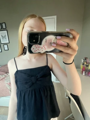 Mörkblå topp med rosette - Svart linnetopp med tunna axelband och en stor rosett framtill. 