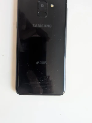 Svart Samsung Galaxy Duos Android - Snygg svart Samsung Galaxy Duos med glasbaksida och fingeravtrycksläsare på baksidan. Telefonen har en stilren design, en stor färgstark skärm och klassisk Samsung-logga. Perfekt för dig som vill ha en pålitlig Android-mobil med plats för två SIM-kort.