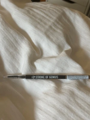 W7 Stroke of Genius Brow Pencil Blonde - Ögonbrynspenna från W7 i färgen Blonde. Pennan har en smal spets för precisa linjer och en borste i ena änden för att forma brynen. Vegansk formula och microblade-effekt för naturligt resultat. Perfekt för att fylla i och definiera ögonbryn. Använd men visas på sista bilden hur mycket som är kvar.