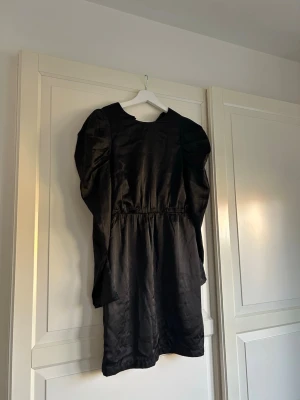 Svart långärmad kortklänning - Stilren svart kortklänning med långa puffärmar och markerad midja. Klänningen har en enkel rund halsringning och är tillverkad i ett glansigt material!!🖤super fin både till sommaren och vintern!!