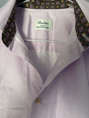 Skjorta från Stenströms - Snygg skjorta från Stenströms med diskreta ränder och blommigt mönster på insidan av krage och manschetter. Skjortan har klassisk krage, knappar framtill och är tillverkad i mjuk bomull. Perfekt för dig som vill ha något unikt i garderoben. Storlek 39 cm.