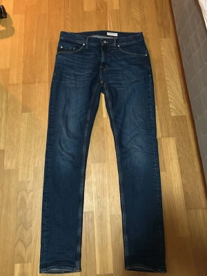 Mörkblå raka jeans från Tiger of Sweden - Snygga mörkblå jeans från Tiger of Sweden med klassisk femficksmodell och raka ben. Jeansen har subtila slitningar och kontrastsömmar. Tillverkade i ett mjukt och stretchigt denimtyg som sitter skönt hela dagen.