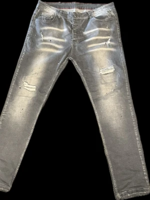 Grå shaded jeans Dsquared2 - Säljer ett par grå jeans Dsquared2 med en balanserad stil och färgstänk för en cool trendig look. Jeansen har fyra fickor, raka ben och en patch med logga bak i midjan. Materialet är klassisk denim i bomull med stretch. Passar 32-33