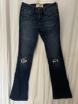 Mörkblå bootcut jeans Hollister - Snygga bootcut hollister jeans med slitningar i knäna. Passar till alla outfits ! Kom privat om ni vill ha midjemått mm
