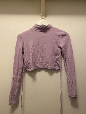 💜 Ljuslila Croppad Polo - ✨ Ljuslila croppad polotopp med långa ärmar och snörning att knyta i ryggen. Öppen rygg och är tillverkad i mjuk bomullsmix. Använd ex antal gånger men i fint skick. Storlek S/36. ✨✨ 