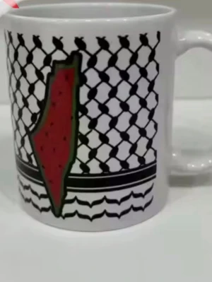 Vit mugg med grafiskt tryck( ny original förpackning  - Vit keramikmugg med svart grafiskt mönster och en röd-grön illustration i mitten. Muggen har ett klassiskt handtag och levereras i en skyddande förpackning. Perfekt för kaffe eller te och sticker ut med sin unika design.