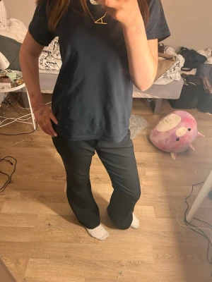 Svarta kostymbyxor med rak passform - Säljer ett par svarta kostymbyxor med rak passform och normal midja. Byxorna har en klassisk look och är perfekta för dig som gillar stilrena och enkla plagg. Materialet känns mjukt och följsamt, vilket gör dem bekväma att bära hela dagen.