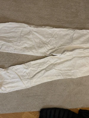 Vita vida linnebyxor - Säljer ett par vita linnebyxor med rak och avslappnad passform. Byxorna är tunna och har en klassisk look som passar perfekt till sommaren. Materialet är linne vilket gör dem svala och sköna. Inga synliga detaljer eller märke.