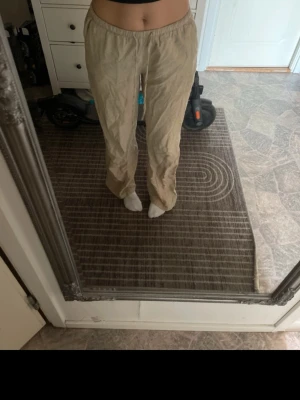 Beiga linnebyxor med resårmidja - Säljer ett par beiga linnebyxor med avslappnad passform och resår i midjan. Byxorna har raka ben och är tillverkade i ett lätt och luftigt linnematerial, perfekta för en chill och stilren look. Inga synliga fickor eller detaljer.