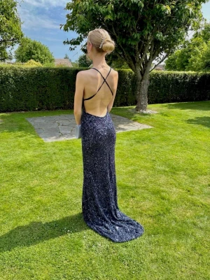 Marinblå balklänning  - Säljer en mycket fin mörkblå balklänning med vacker mönstring och massa glitter! Klänningen har smala och justerbara axelband, djup rygg och ett lätt släp. Perfekt för bal, bröllop, gala eller annan festlig tillställning. Endast använd en gång och är fortfarande i mycket bra skick! Nypris på 3999kr. Säljs då den inte kommer till användning för mig igen.                                                              Hör gärna av dig vid frågor eller om du vill ha fler bilder!