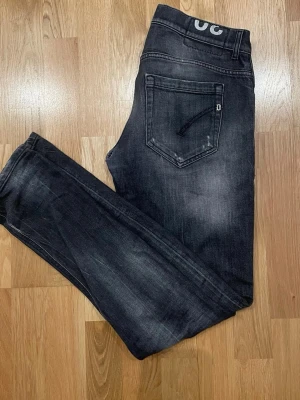Dondup George  - Säljer ett par svarta slim fit jeans från Diesel med snyggt slitna detaljer och klassisk femficksmodell. Jeansen har en diskret logga på bakfickan och är tillverkade i stretchigt denim för extra komfort. Perfekta för en trendig och avslappnad look. 