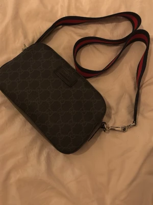 Svart axelväska från Gucci - Snygg svart axelväska från Gucci med klassiskt GG-mönster one size repen går ej att minskas