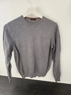 Grå stickad tröja från Stenströms - Mjuk och stilren grå stickad tröja från Davida i klassisk modell. Tröjan har rund halsringning, långa ärmar och ribbade muddar vid ärmslut och nederkant. Perfekt basplagg i garderoben och enkel att matcha.