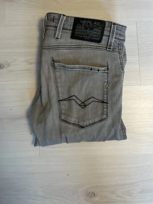 Replay jeans - Snygga grå jeans från Replay med klassisk femficksdesign och coola kontrastsömmar på bakfickan. Jeansen har en rak passform och är tillverkade i mjukt denimtyg. Perfekta för en avslappnad och trendig look. Storlek 30/30 anbass slimfit