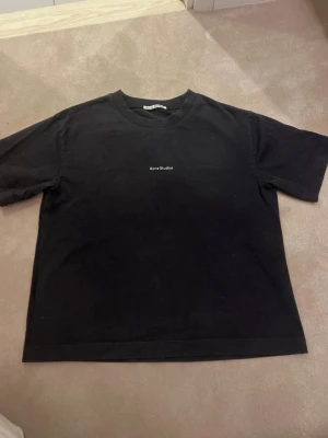 Svart Acne Studios t-shirt - Säljer en svart t-shirt från Acne Studios i jättefint skick!! äkta, jag köpte den på vinted men förra ägaren köpte den på jackie! (förra ägarens bilder, kan självklart fixa egna om det önskas)❤️