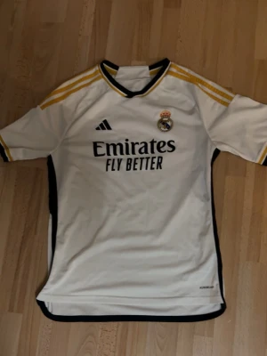 Real Madrid  - Vit Real Madrid matchtröja från Adidas med svarta och gula detaljer. 23/34 säsongen.