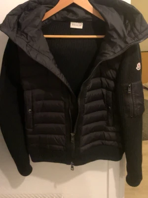 Svart cardigan från Moncler - Snygg svart cardigan från Moncler tvär skön att ha på sig och göra varje outfit snyggare den är så för liten för mig nu så säljer den mycket bra skick och man kan scanna moncler märket sen kan du ladda ner en app och välja vad du vill att de ska stå när du scannar 