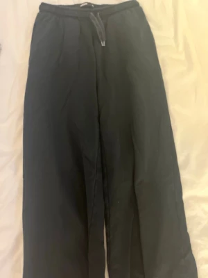 Svarta mjukisbyxor från BikBok💞 - Svarta mjukisbyxor från BikBok med bred resår i midjan och dragsko. Byxorna har raka ben och är gjorda i ett mjukt, bekvämt material som passar perfekt för chill dagar. Klassisk och enkel design utan synliga loggor på benen. Lågmidjade💞