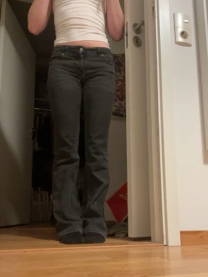 Grå/svarta låg midjade bootcut jeans från Lee - Ett par grå/svarta lågmidjade bootcut jeans från Lee. Det är elastiska och väldigt sköna!! Det är normala i storlek och läng. Modellen Jessica.
