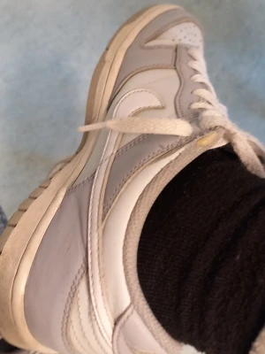 Nike vita låga sneakers - Säljer ett par klassiska vita Nike sneakers med lågt skaft och den ikoniska swoosh-loggan på sidan. Skorna har vita snören och en slitstark gummisula. Perfekta för dig som gillar en clean och stilren look till vardagsoutfiten.SIZE 38 100 PROCENT ORIGINIAL