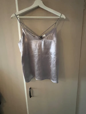 Silvrig linnetopp med smala axelband - Super fint fest  linne med jämt cool färg. Den är reflekterande i ljus och perfekt till en utekväll💓💓