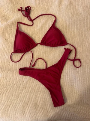 Röd trekantsbikini med knyt - Snygg röd bikini med trekantsmodell på överdelen och smala band som knyts i nacken och ryggen. Aldrig använd