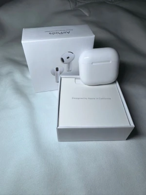 Apple AirPods med laddningsetui - Säljer ett par vita Apple AirPods med trådlöst laddningsetui. Snygg och stilren design i blank plast, perfekt för dig som vill ha smidiga in-ear hörlurar med grymt ljud och enkel anslutning till iPhone eller andra Apple-enheter. Levereras i originalförpackning.