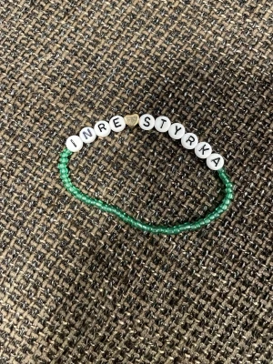 Grönt pärlarmband med text - Armband med små gröna pärlor och vita bokstavspärlor som stavar 'INRE STYRKA'. Ett litet guldfärgat hjärta sitter mellan orden. Perfekt accessoar för dig som gillar personliga smycken.